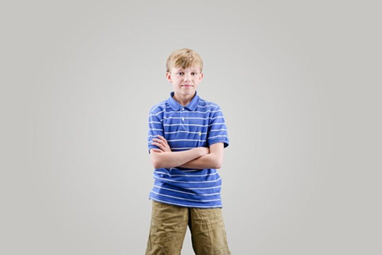 A boy is looking on the camera on a studio background