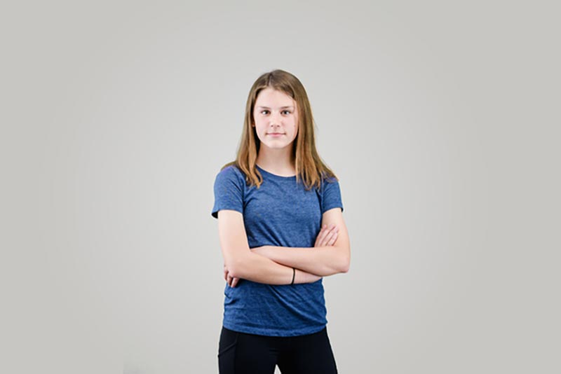 A girl is looking straight to the camera in a studio background