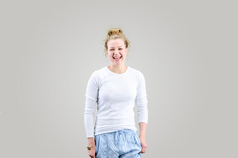 A woman is playfully smiling on a studio background